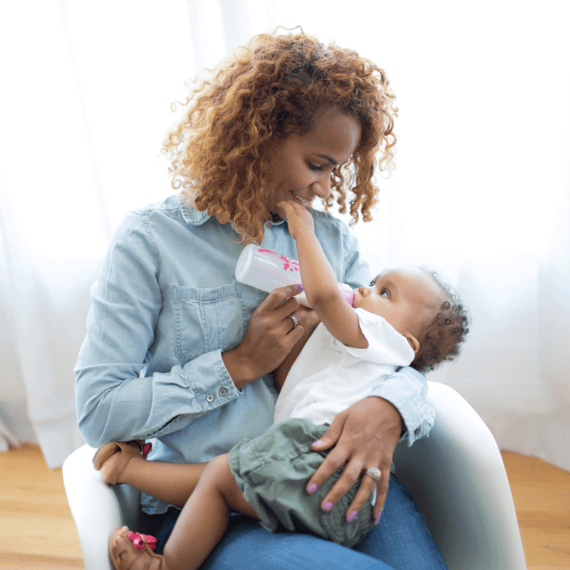 women holding baby and feeding from baby bottle