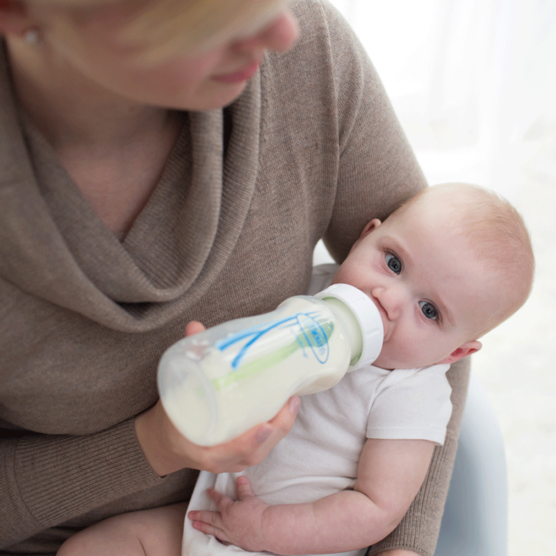 women holding baby and feeding from baby bottle