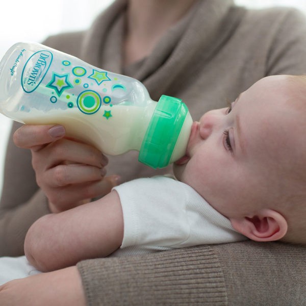 mom holding baby drinking from a Dr. Brown's sippy bottle with green stars