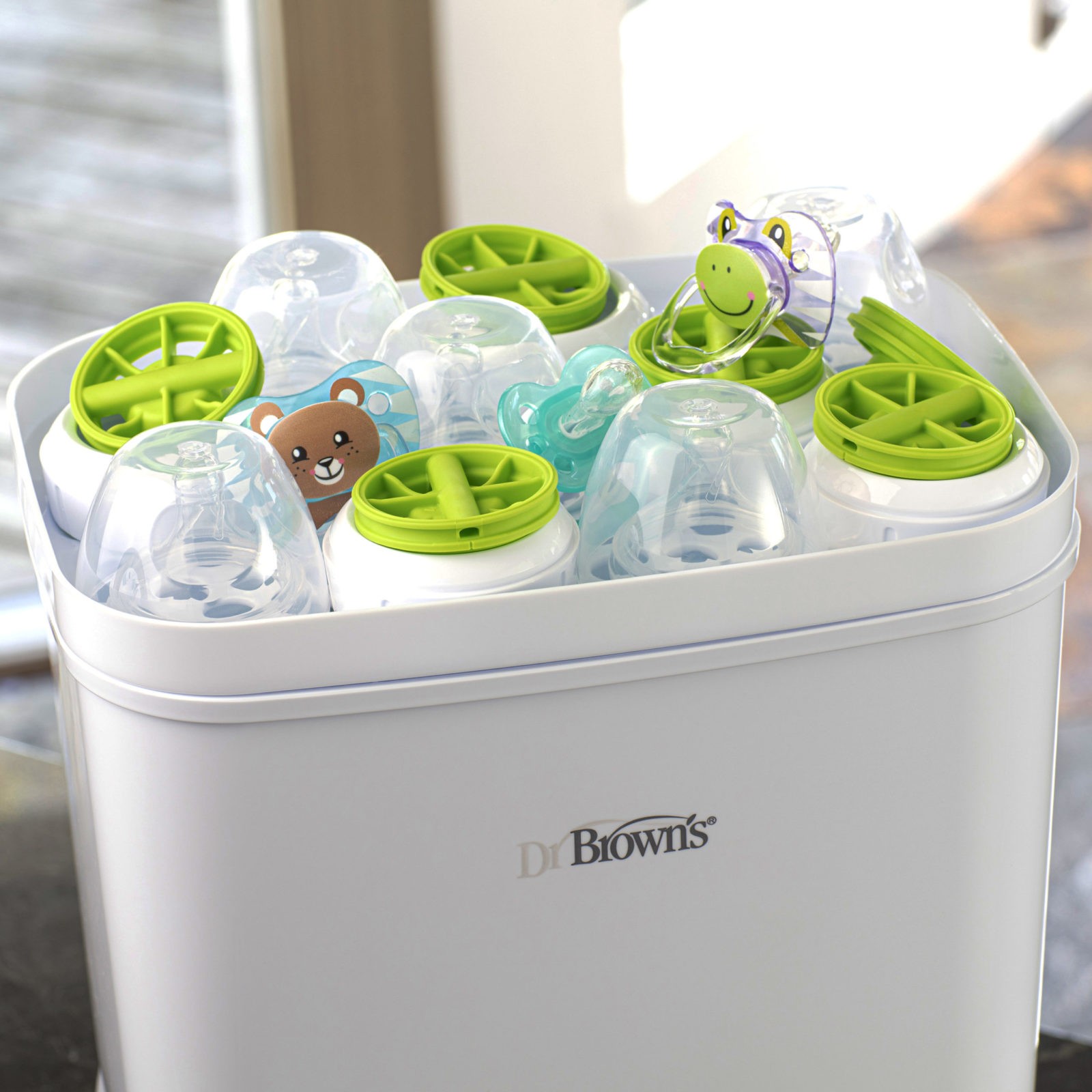 Lifestyle_Clean_Steam_Sterilizer_and_Dryer_top_accessories_tray_2 Upclose photo of sterilizer open with parts, nipples, and pacifiers on tray